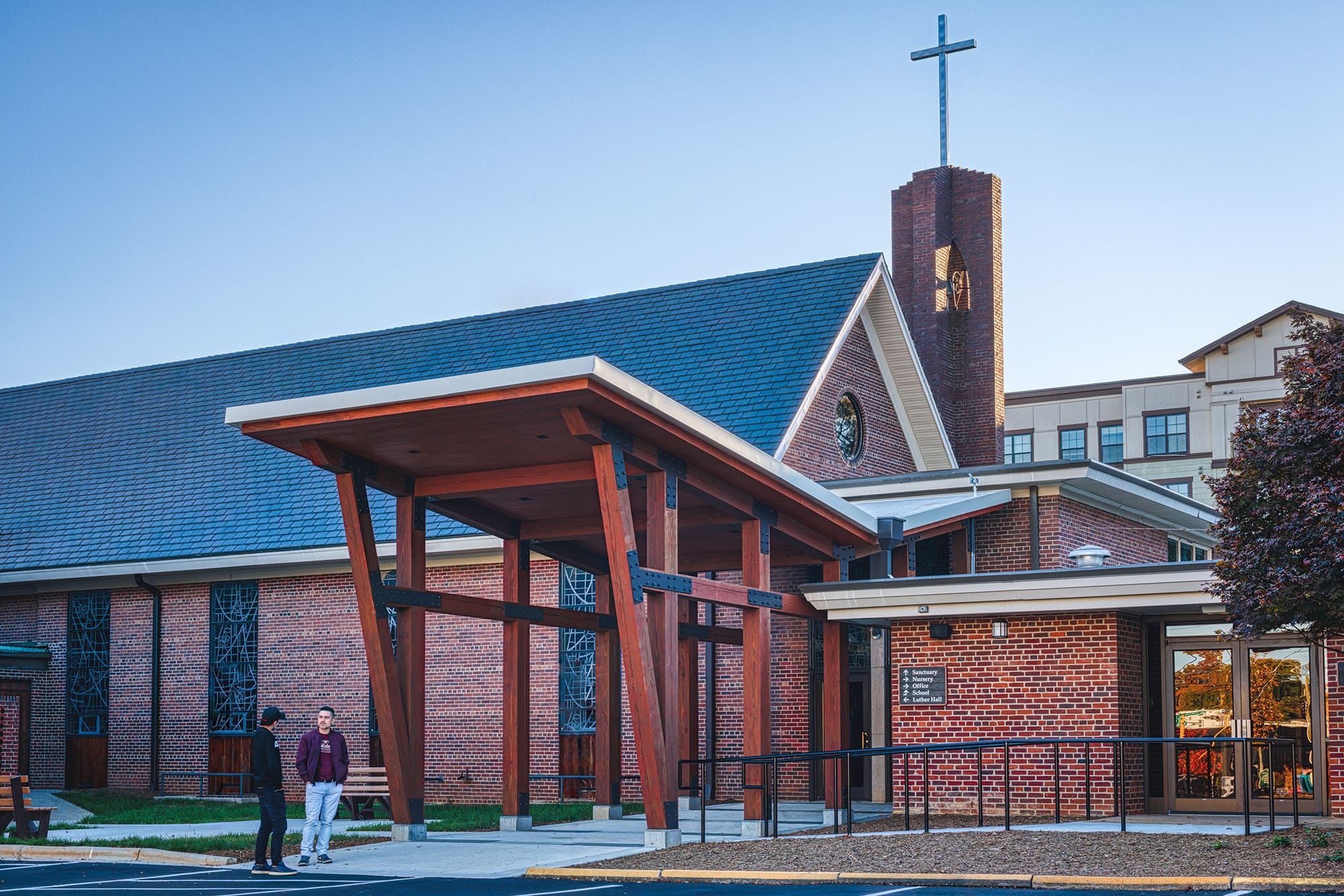 Ascension Church in Charlotte, NC with the new timber entry canopy beside the brick sanctuary, tower and cross by Ossa Studio