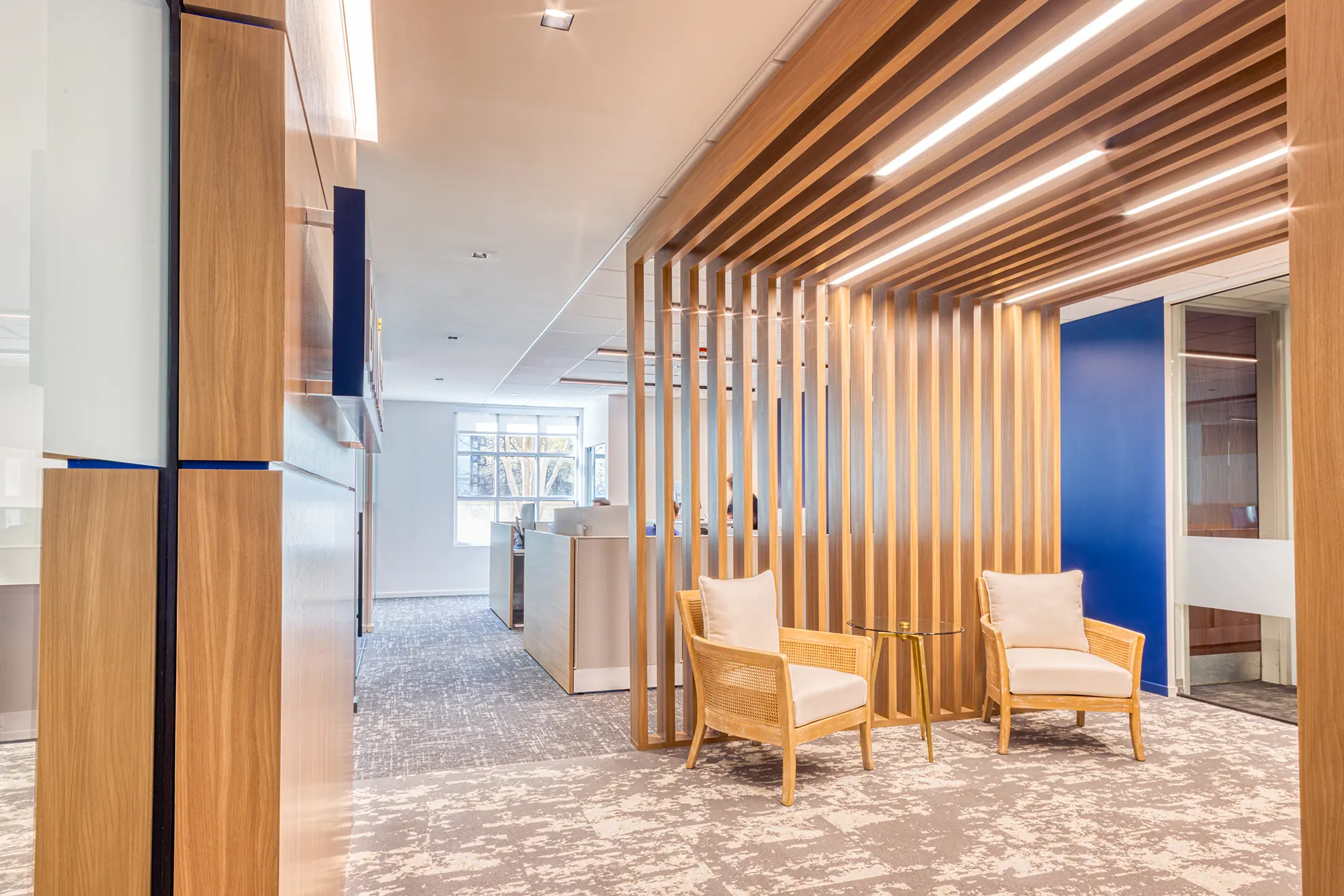 BWM Wealth Strategies office lounge in Charlotte, NC, framed by architectural wood slats with integrated lighting and seating by Ossa Studio.
