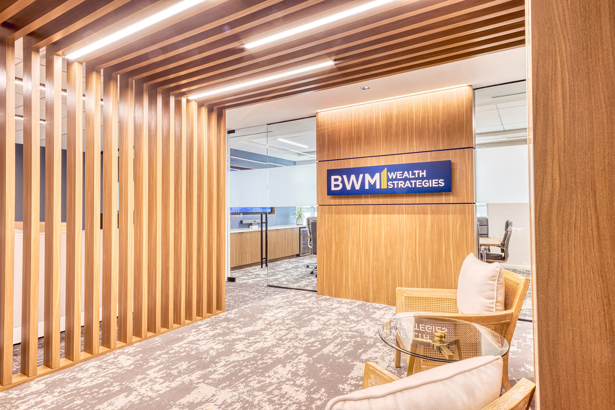 BWM Wealth Strategies reception area in Charlotte, NC, featuring custom wood paneling, illuminated slats and glass partitions by Ossa Studio