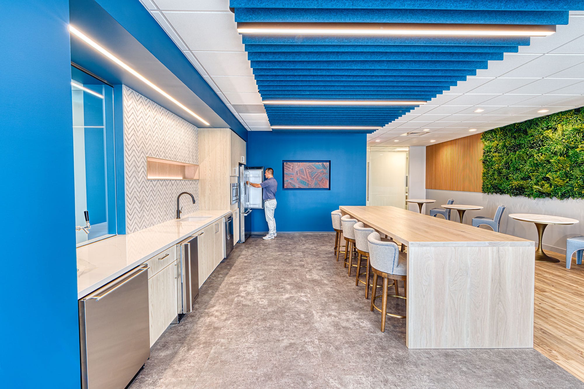 Breakroom and lounge at Collet in Charlotte, NC with a long wood table, blue ceiling baffles and a green wall by Ossa Studio
