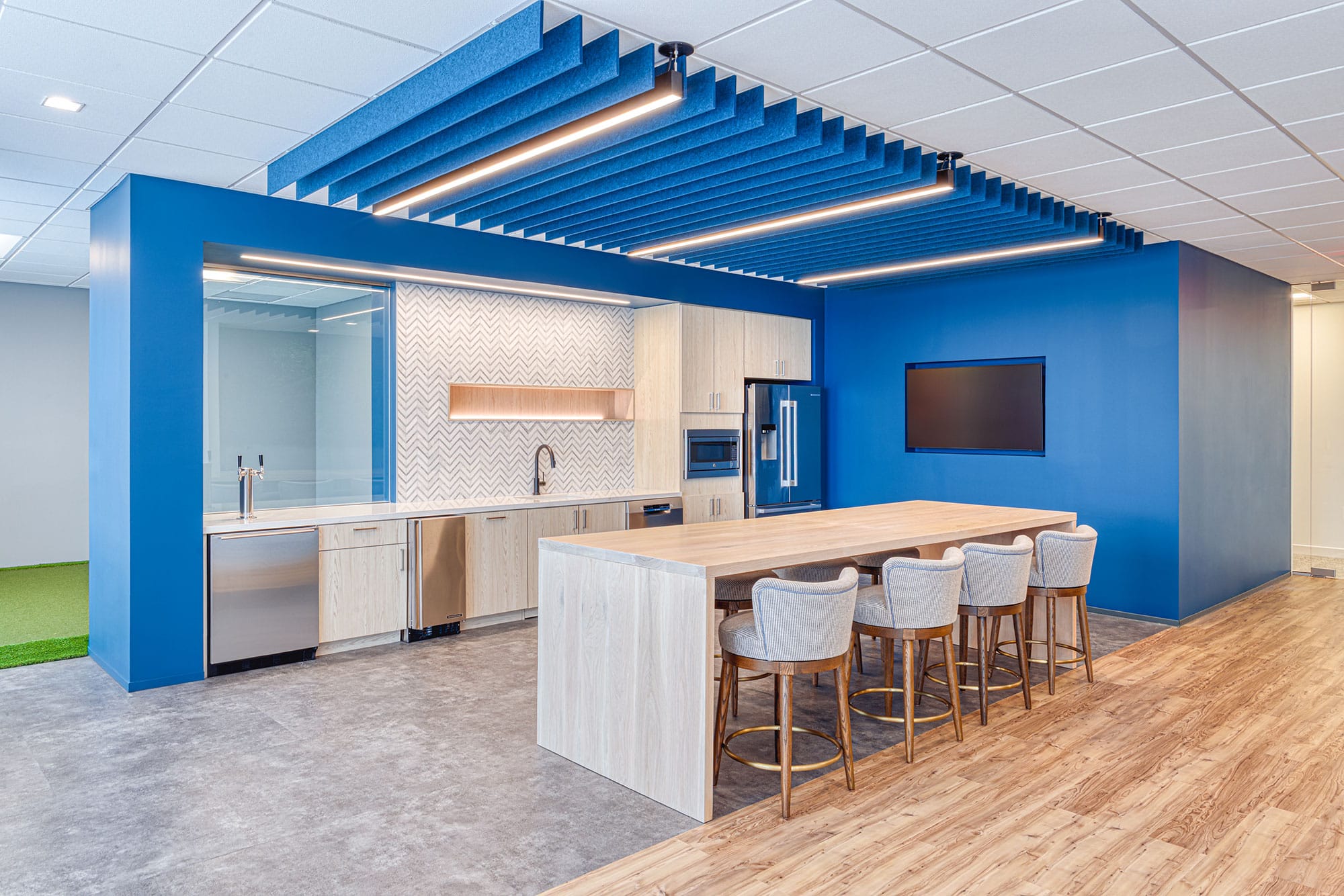Office kitchen at Collet in Charlotte, NC with a light wood island, chevron backsplash and blue acoustic baffles by Ossa Studio