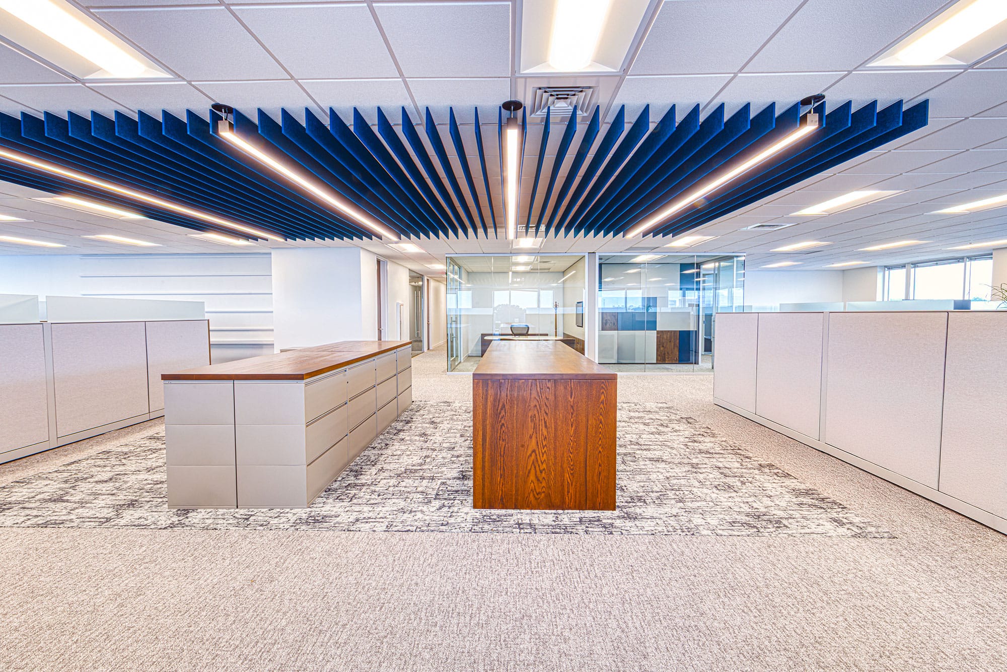 Open office at Collet in Charlotte, NC with storage islands, a wood work table and continuous blue ceiling baffles by Ossa Studio
