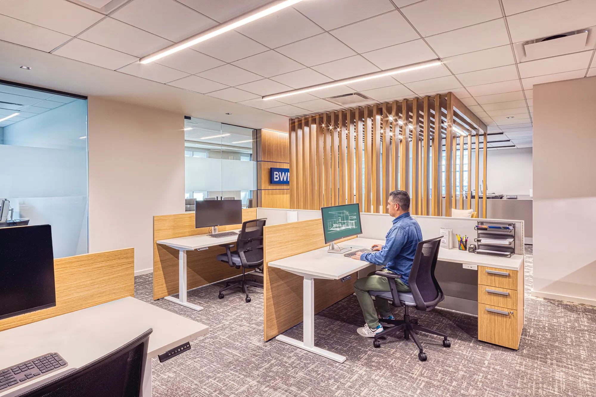 Open office with glass partitions and a wood slat feature wall in the BWM Wealth Strategies office in Charlotte, NC, by Ossa Studio