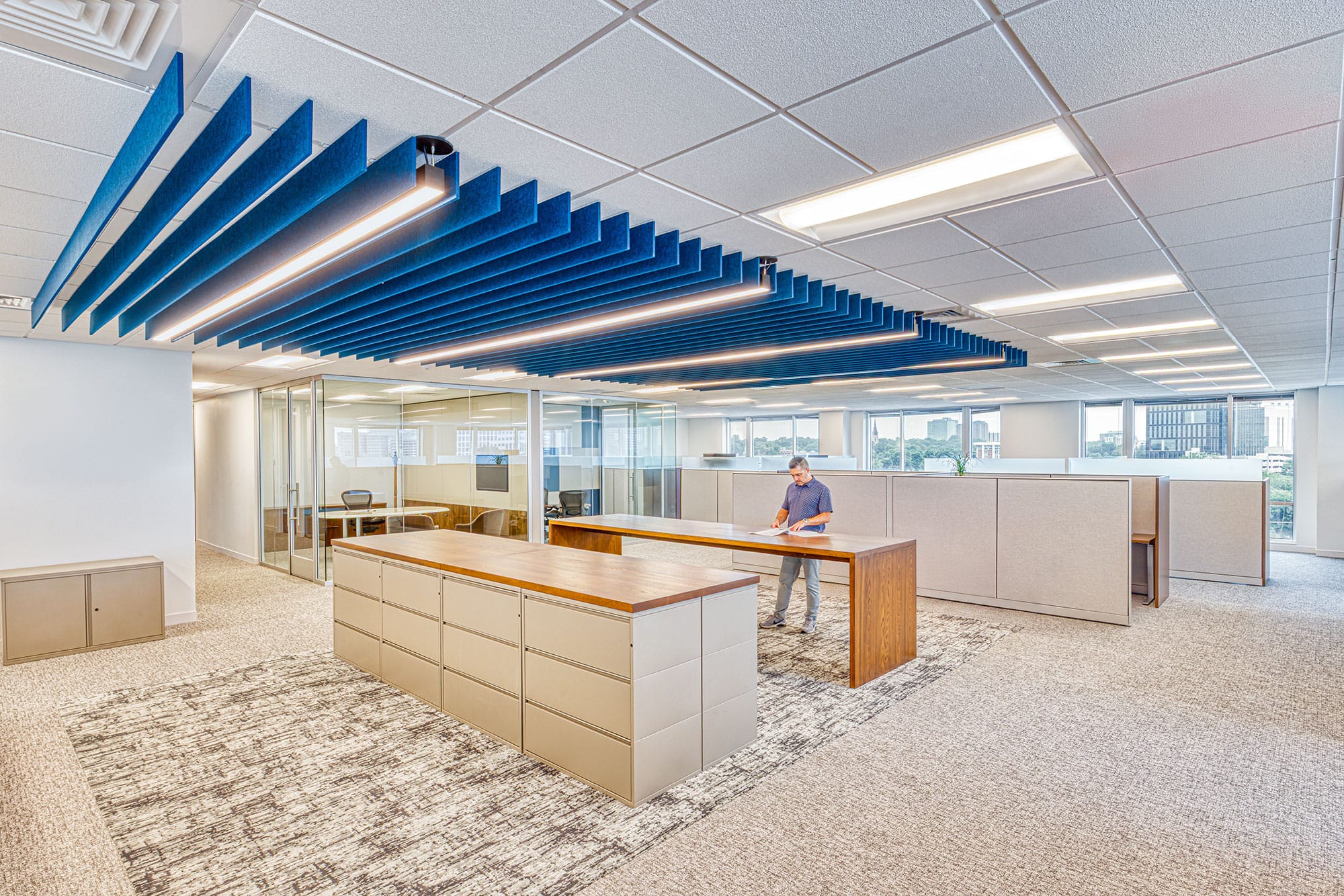 Open office with glass meeting rooms and linear lighting in the Collet office in Charlotte, NC, designed by Ossa Studio