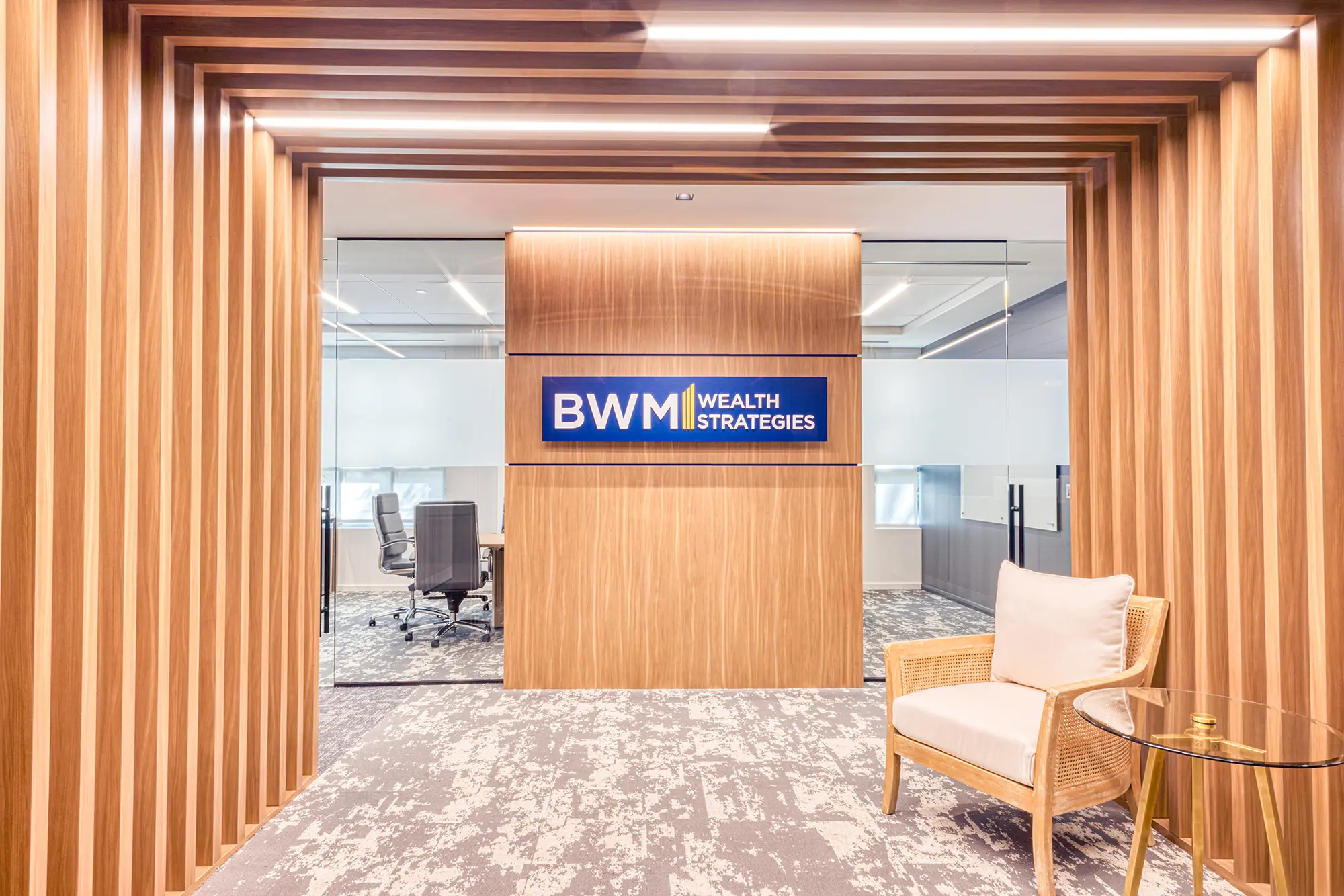 Reception with a wood slat wall, integrated lighting and a brand wall in a Charlotte office upfit by Ossa Studio