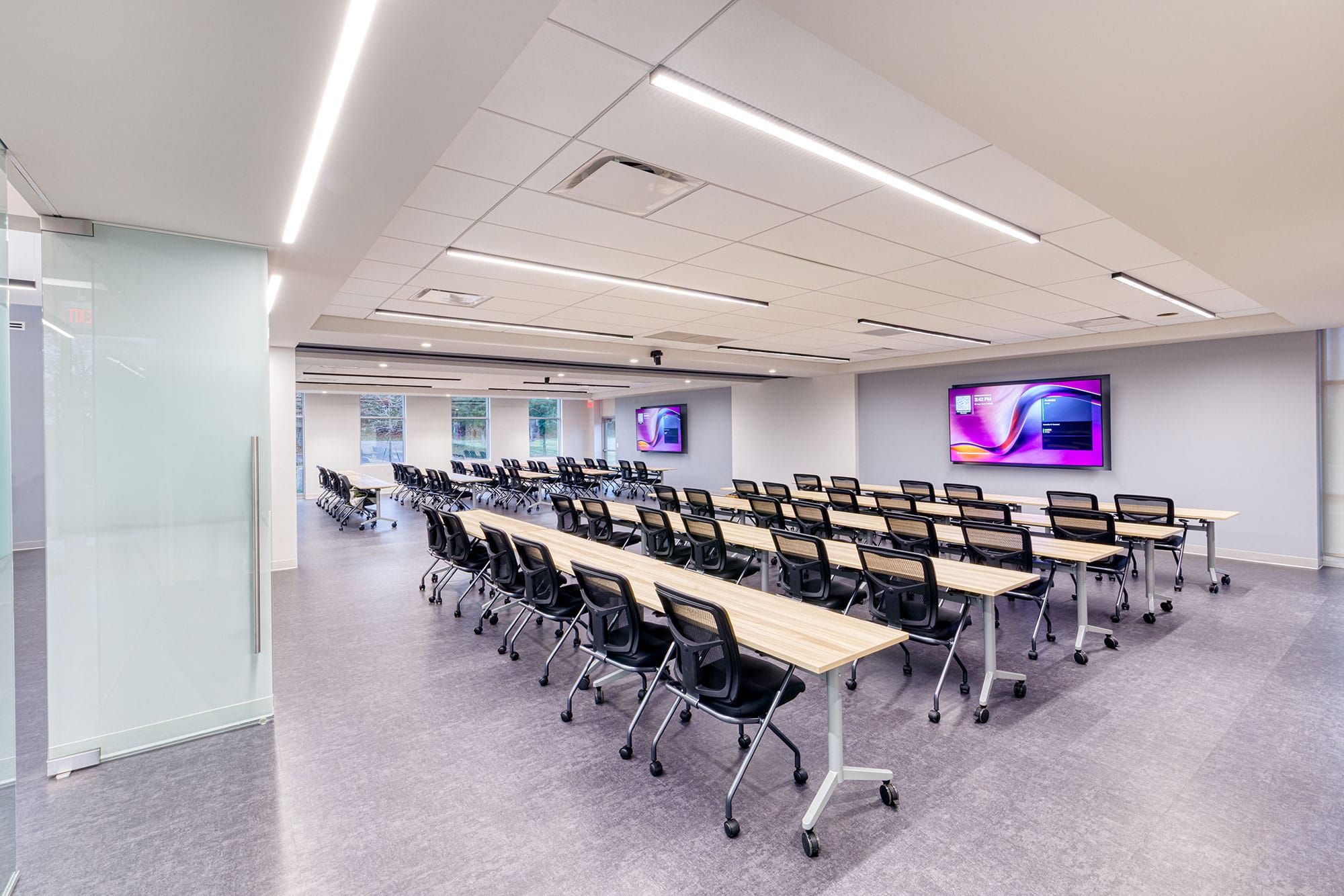 Training room at Crowder Construction in Charlotte, NC with rows of long tables, wall screens and a glass partition by Ossa Studio