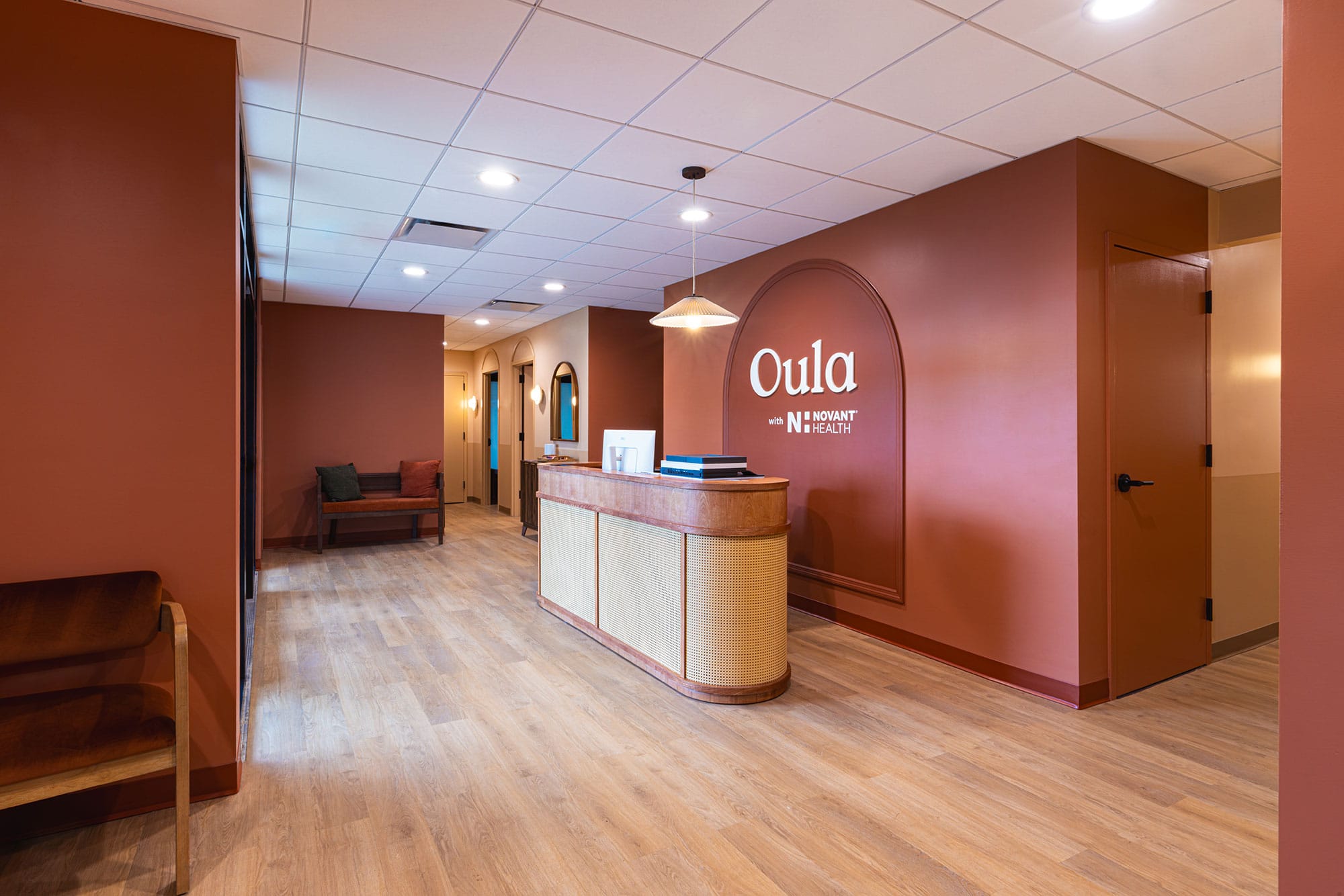 Entry and reception area of the Oula Health clinic in Charlotte, NC with custom millwork, warm finishes and wood flooring by Ossa Studio