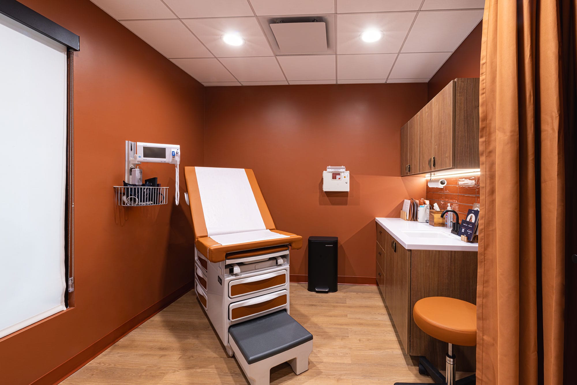 Patient room at Oula Health in Charlotte, NC with terracotta walls, wood cabinetry, residential furnishings and natural light by Ossa Studio