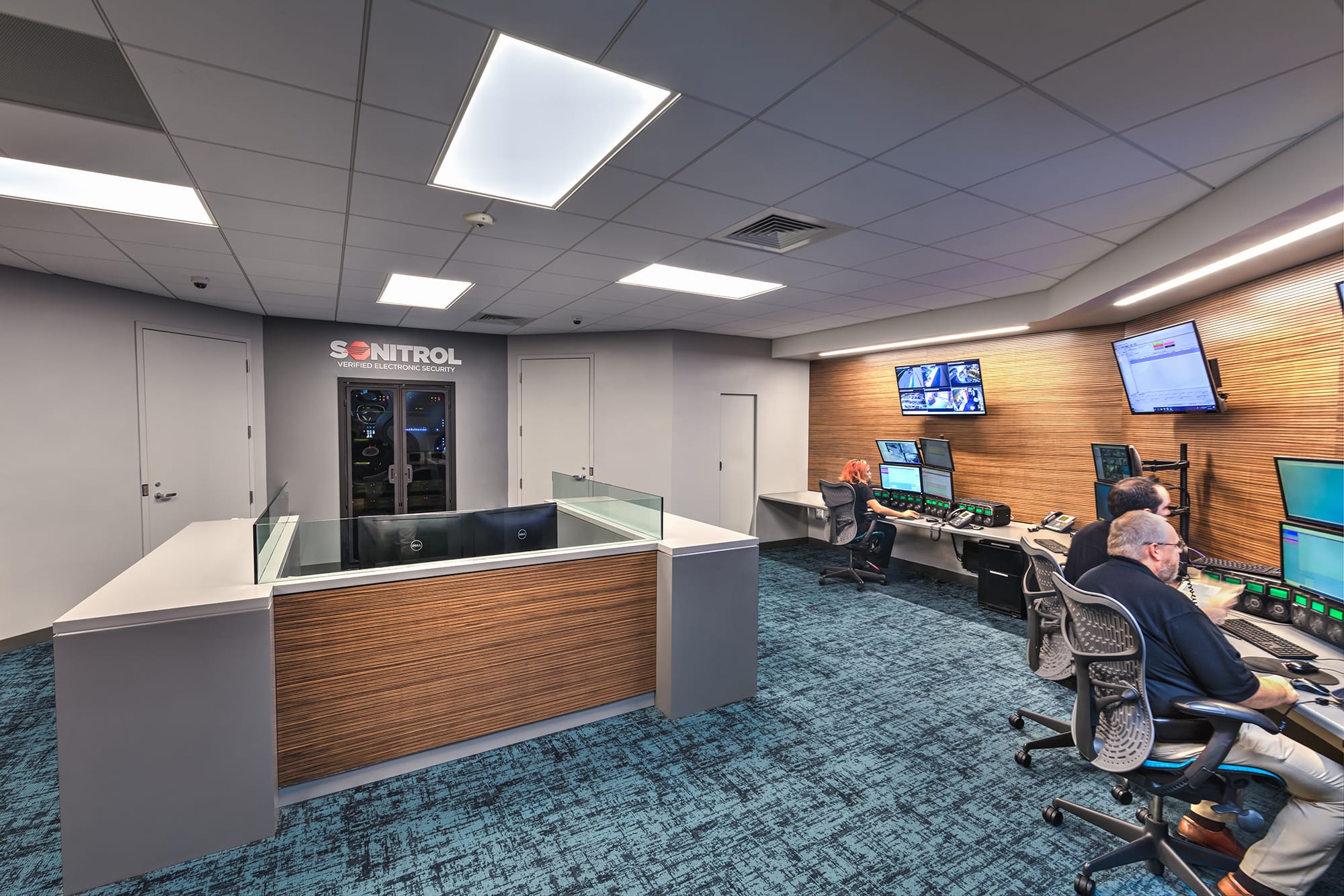 Sonitrol logo wall, glass-topped front desk and operator stations inside the Sonitrol Control Room in Charlotte, NC by Ossa Studio