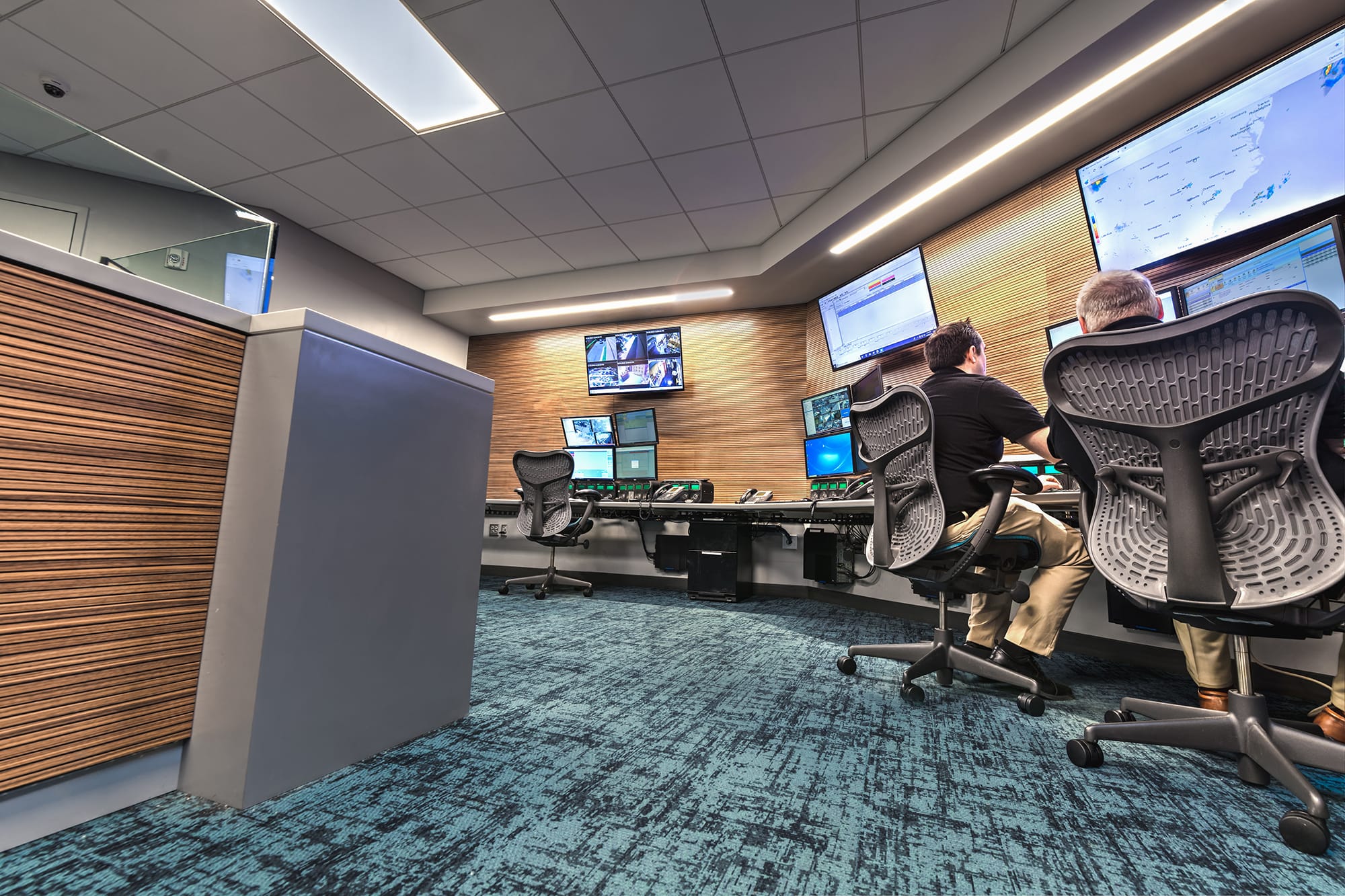 Operators seated at monitoring workstations under wall displays in the Sonitrol Control Room in Charlotte, NC, designed by Ossa Studio