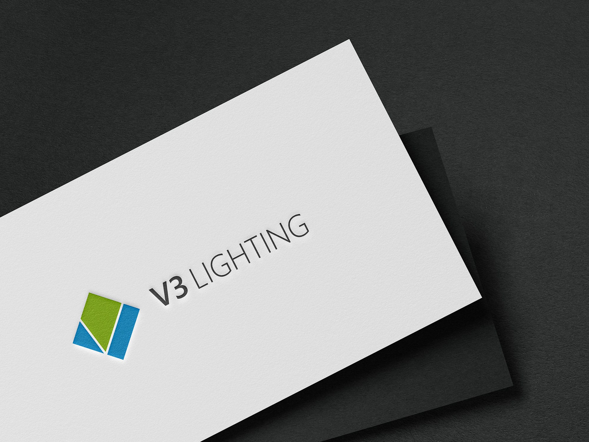 V3 Lighting logo embossed on white card stock over dark paper, part of the brand identity designed by Ossa Studio in Charlotte, NC