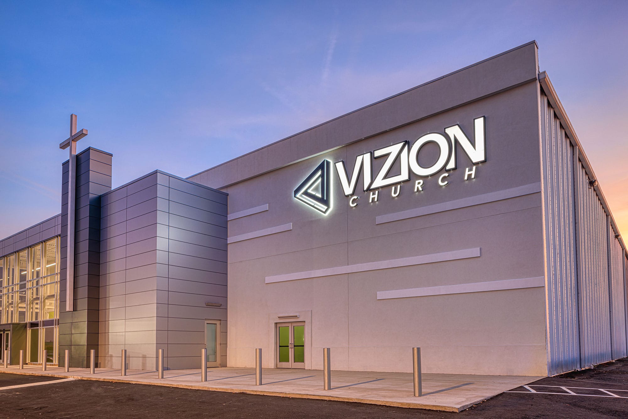 Exterior of Vizion Church in Charlotte, NC with illuminated church signage, contemporary facade and cross tower by Ossa Studio